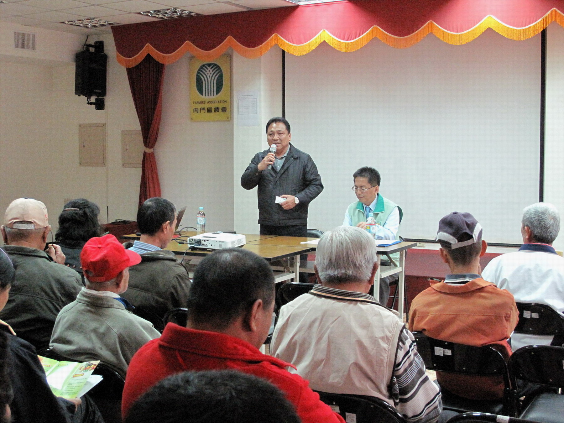 洪輝煌總幹事（左）向農民說明農會新願景